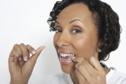 Woman flossing teeth, studio shot